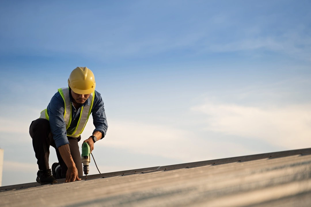 Commercial Roofing-worker drilling and roofing constraction